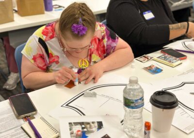 Woman with a flower hairclip applies glue to a photo while working on a creative worksheet.
