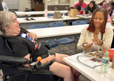 Woman in a wheelchair laughs while working on a project with her DSP is using glue.