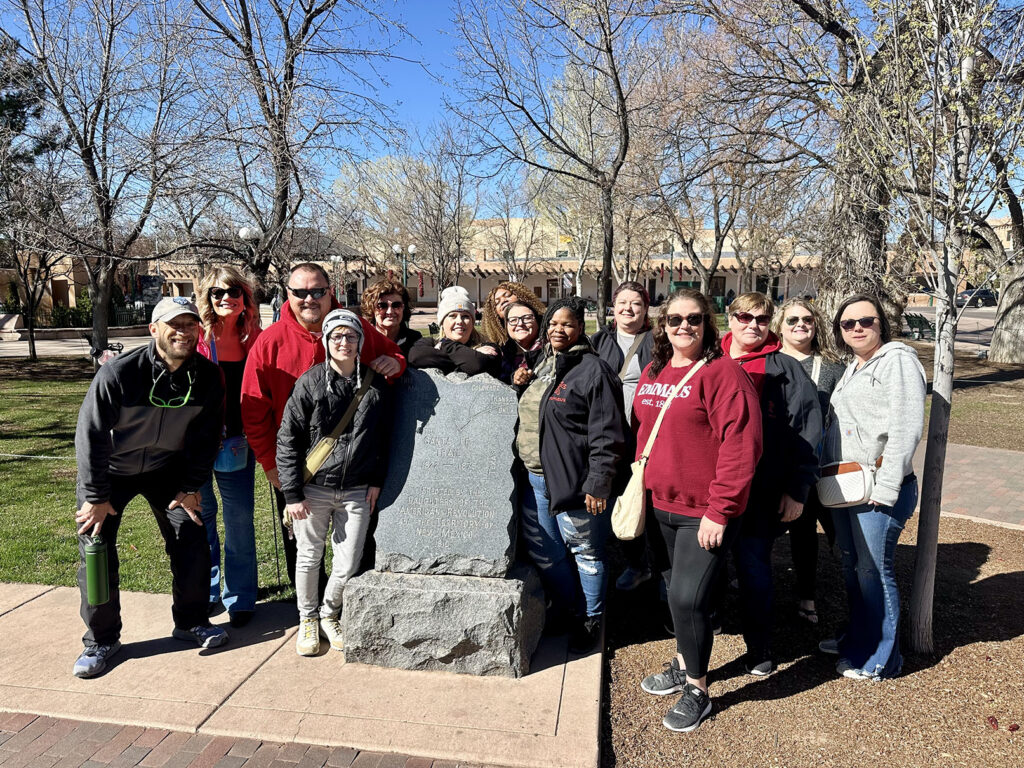 Emmaus employees attending the ANCOR Conference, smiling together outdoors near a historical monument, representing professional growth and team connection.