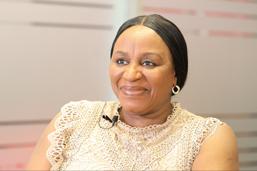 A woman smiling warmly during her interview, wearing a cream lace top.