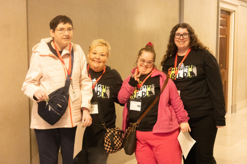 Four Emmaus self-advocates and supporters wearing DRLD badges pose together at the Missouri Capitol during Disability Rights Legislative Day.