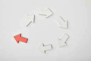 A circular arrangement of arrows, with five white arrows moving clockwise and one red arrow pointing counterclockwise, symbolizing breaking a repetitive cycle.